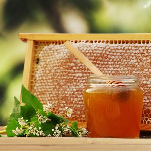 Honig im Glas mit voller Wabe dahinter